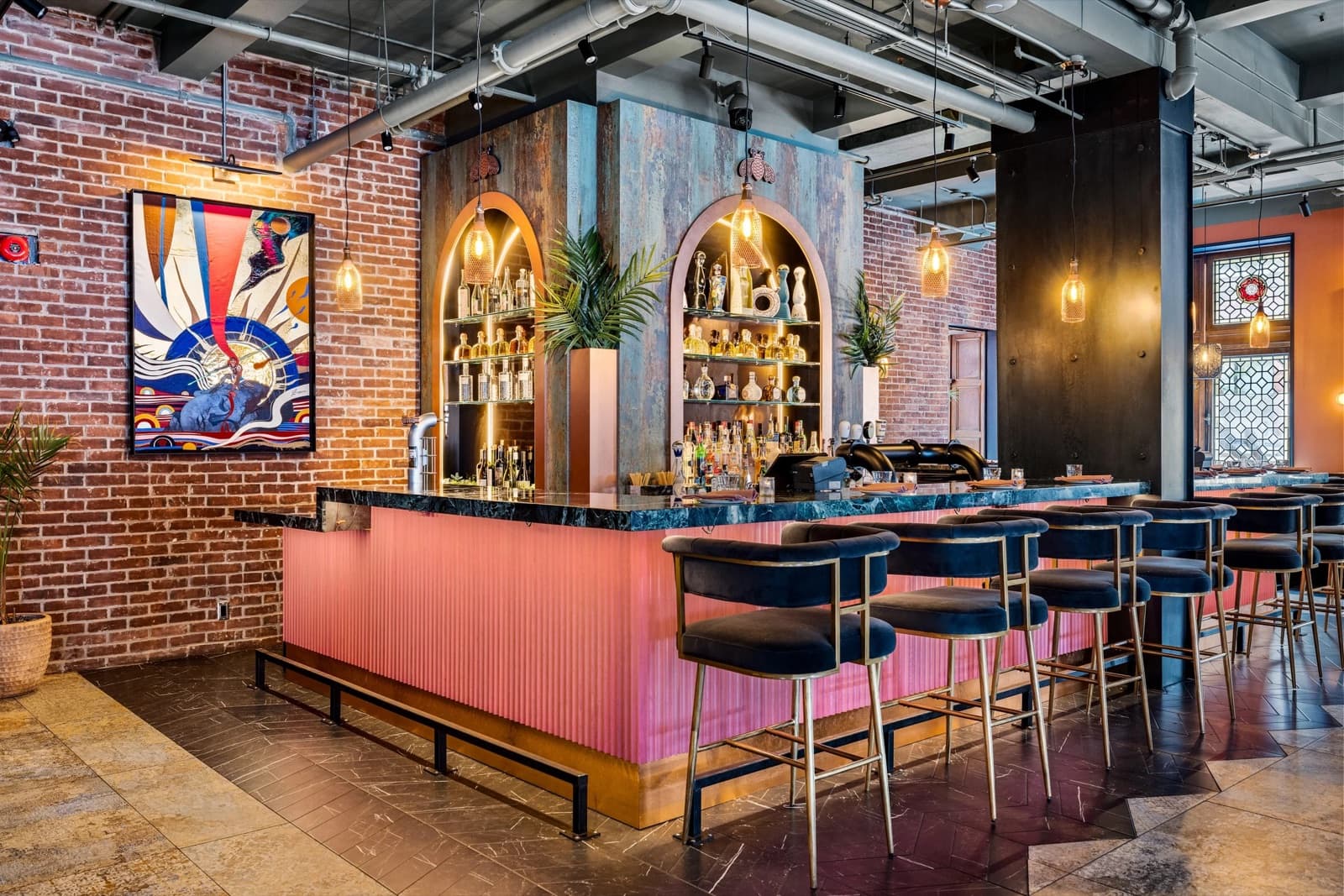 The bar at Aitch, under arched backlit shelves