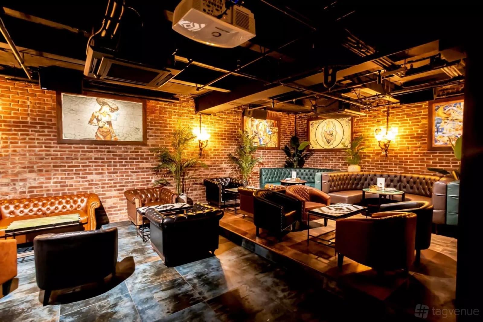 Aitch's lounge: brick walls, leather chesterfields and low tables under warm sconces