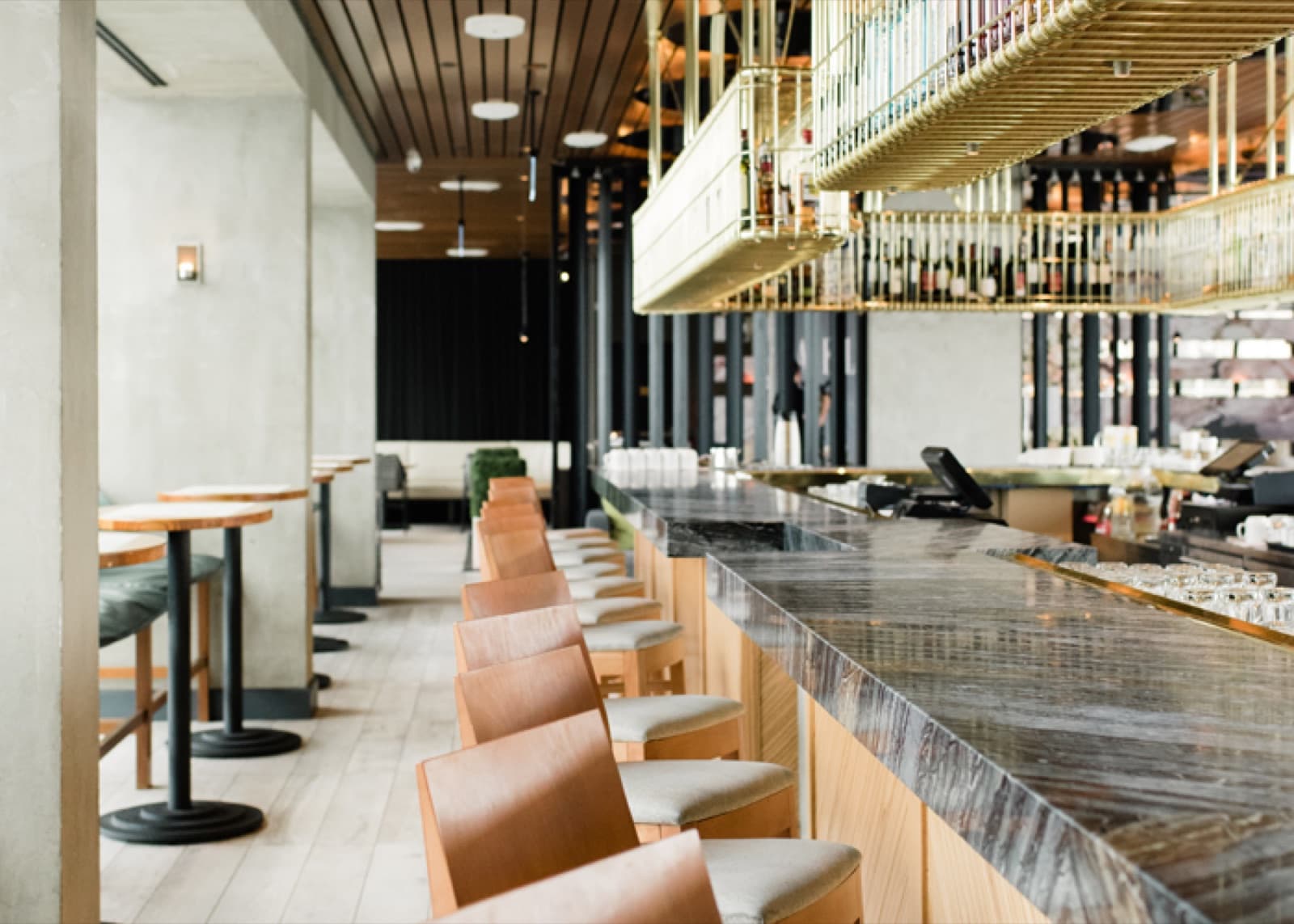 Lavelle's long marble bar with leather stools under a wood ceiling