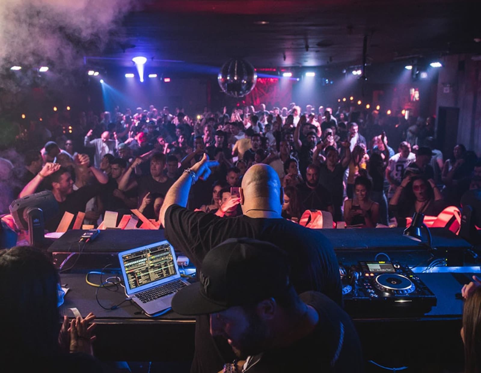 A packed dance floor at Nest seen from behind the DJ decks