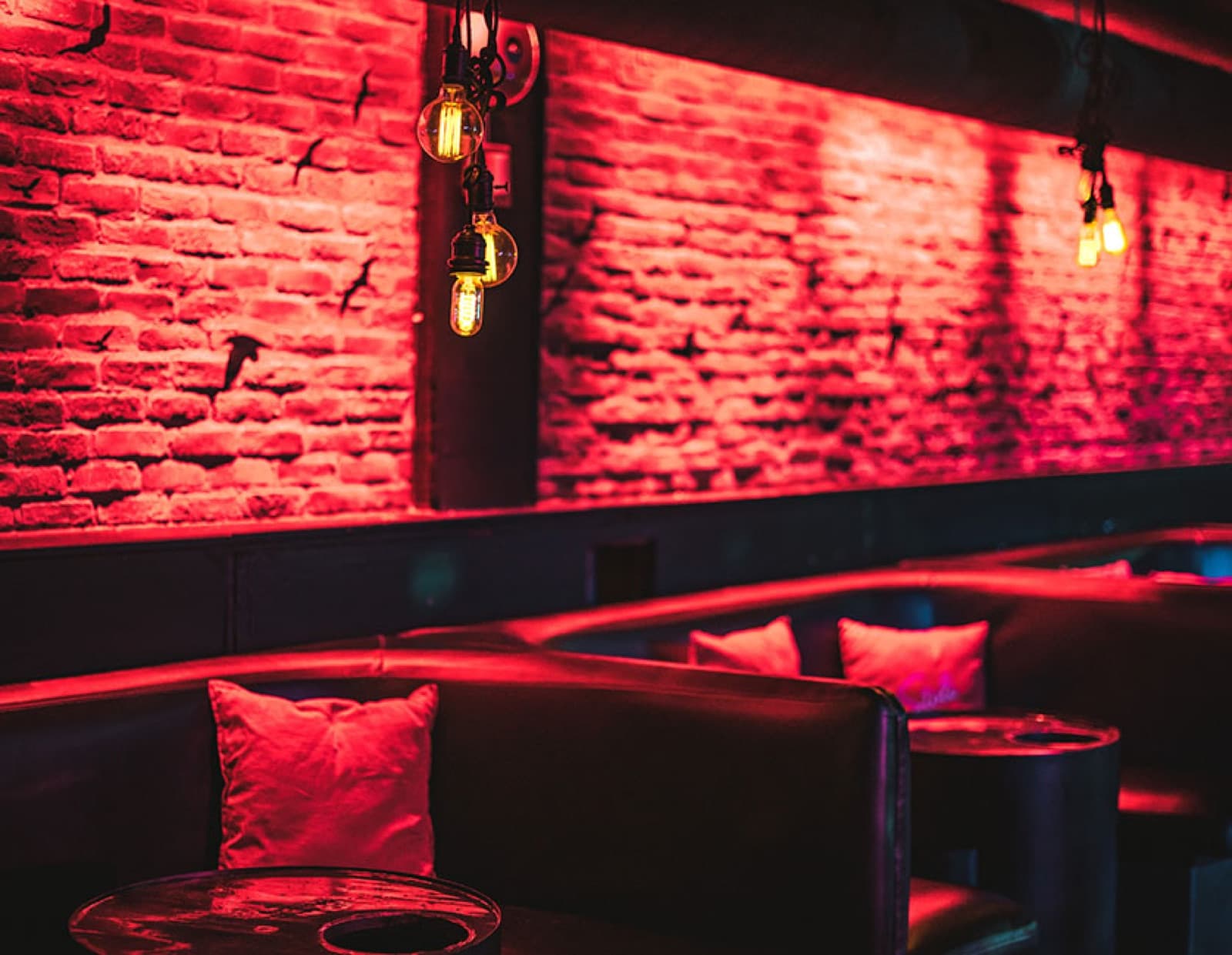 Booth seating against a red-lit brick wall at Nest