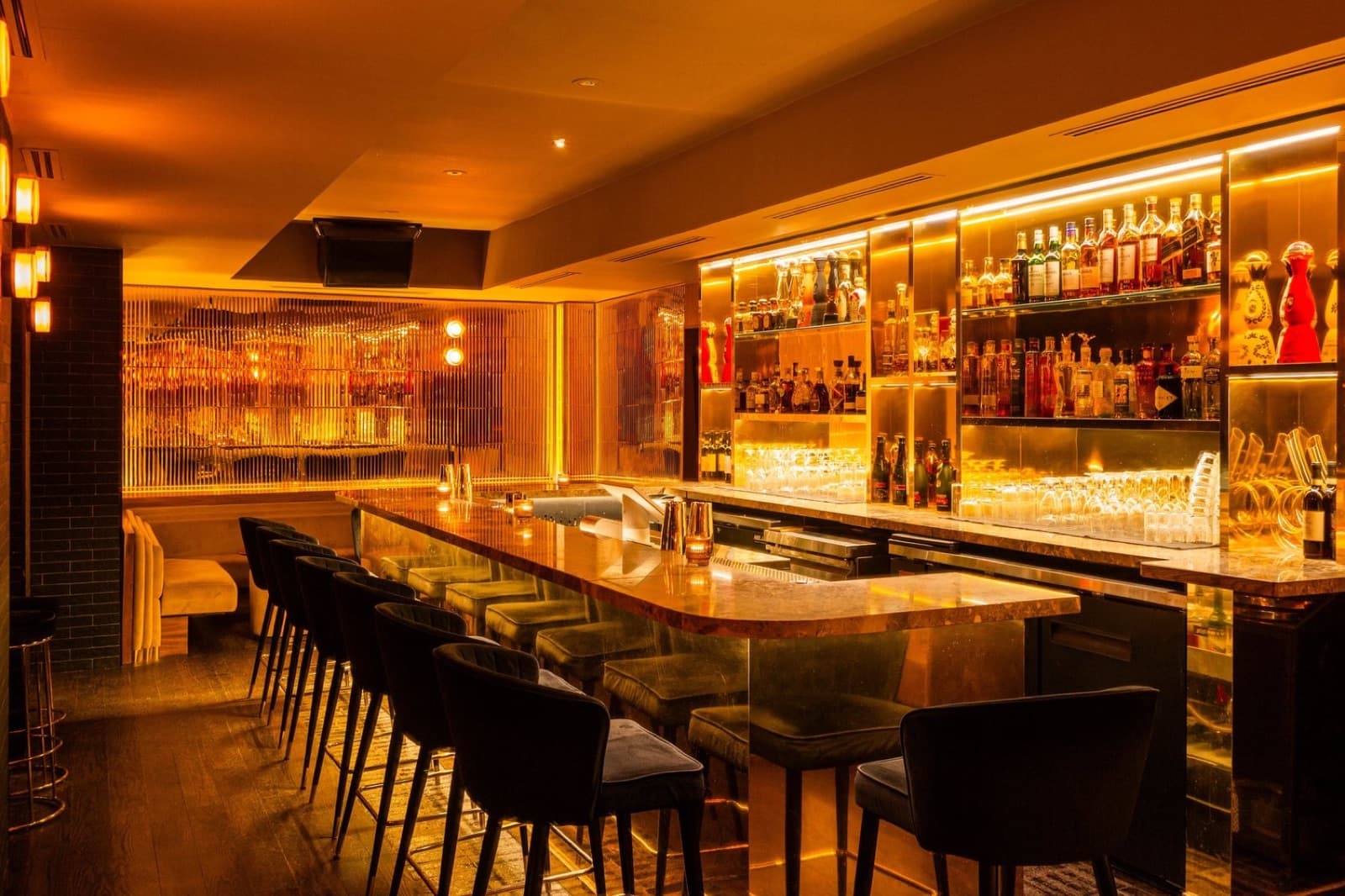 The bar at Parc Ave, lit gold, with a row of stools