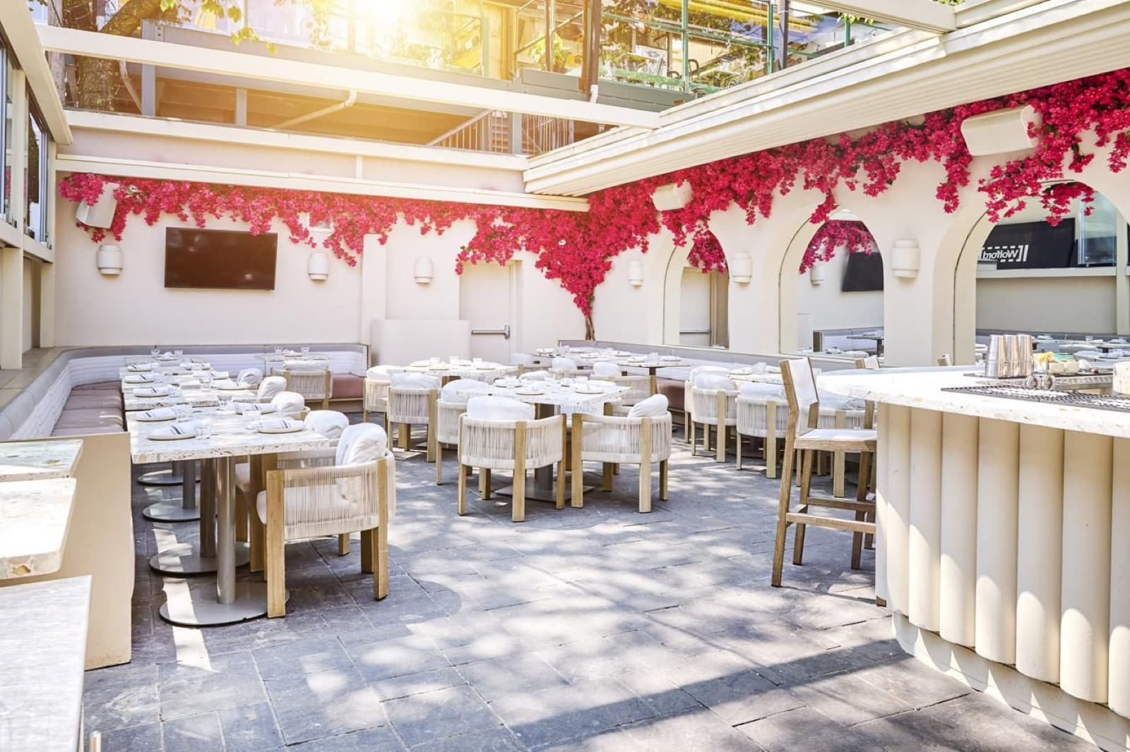 Paros's patio in daylight: white arches, bougainvillea and rows of tables under an open roof