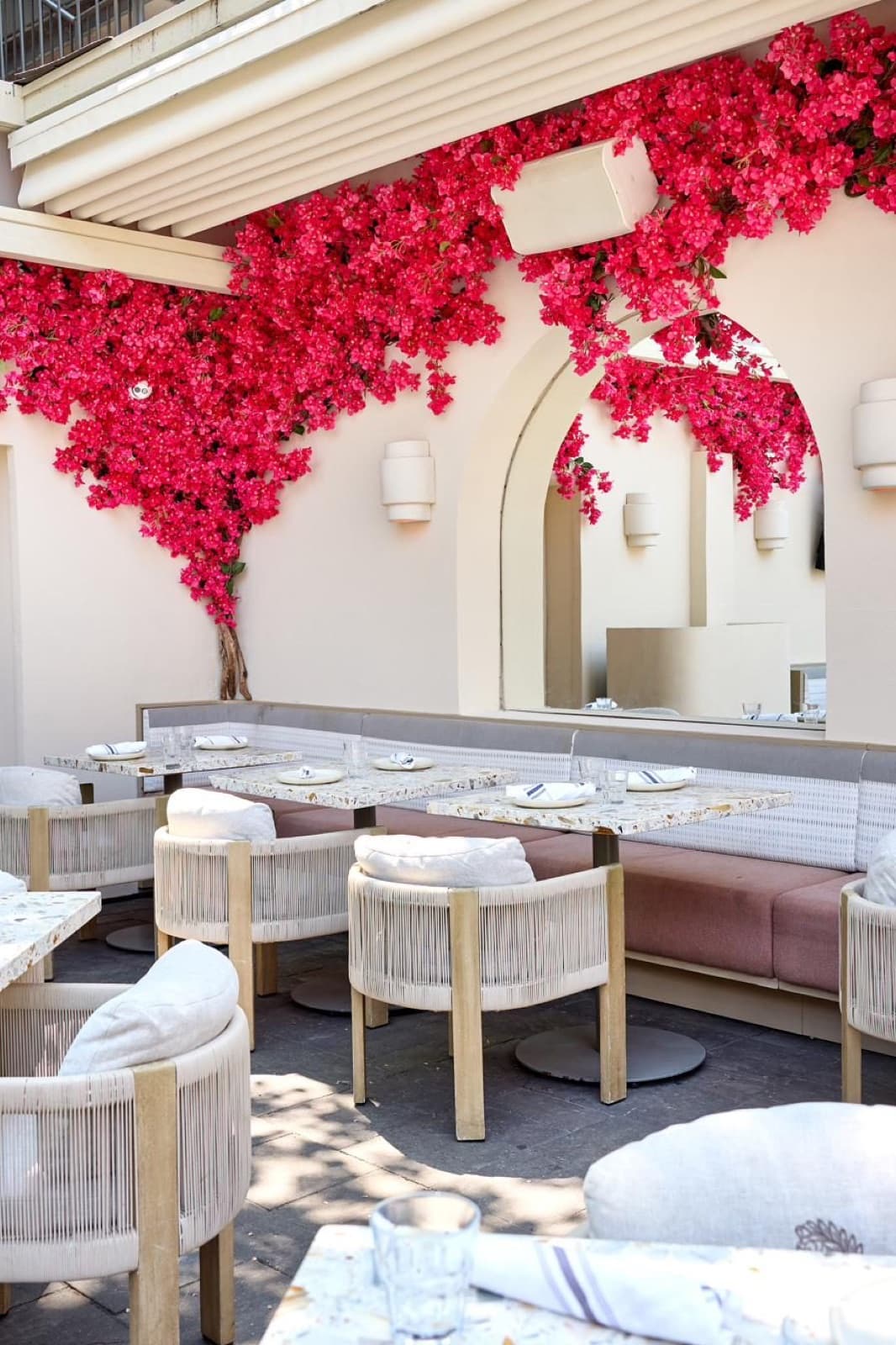 Patio tables beneath arches draped in pink bougainvillea