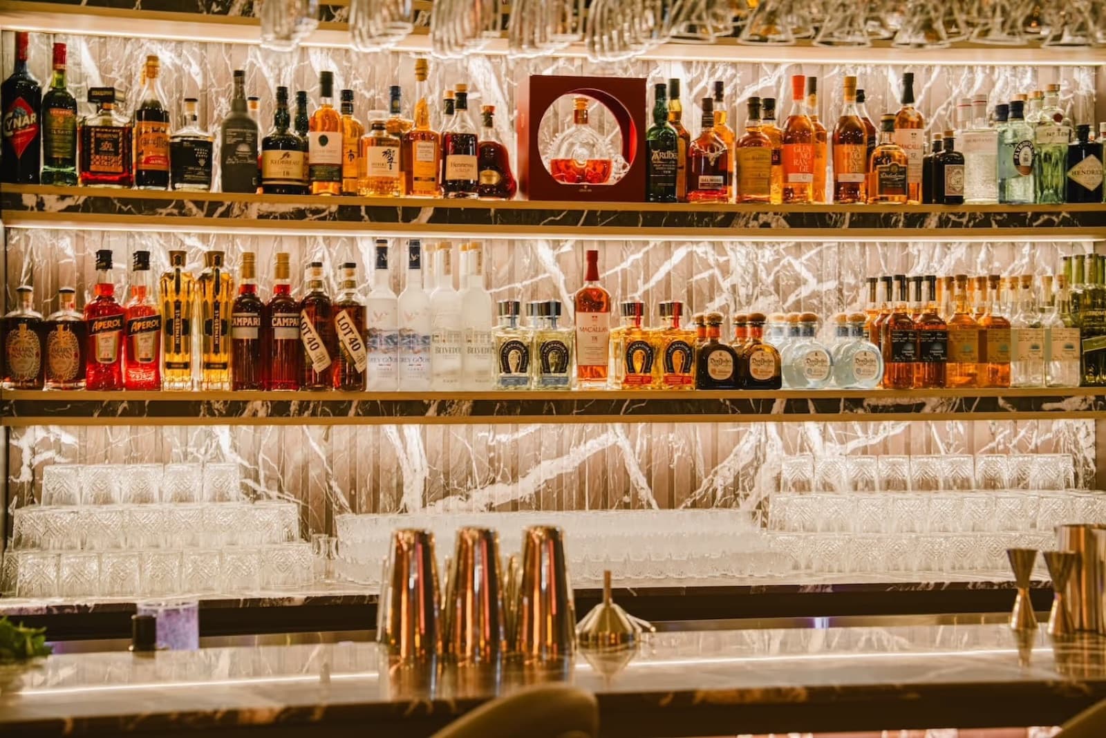 The back bar at Powder Room, shelves of bottles lit from below